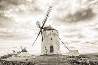 Consuegra, Ciudad Real, İspanya 'daki yel değirmenlerinin yakınındaki kırsal yolun siyah beyaz panoramik görüntüsü..