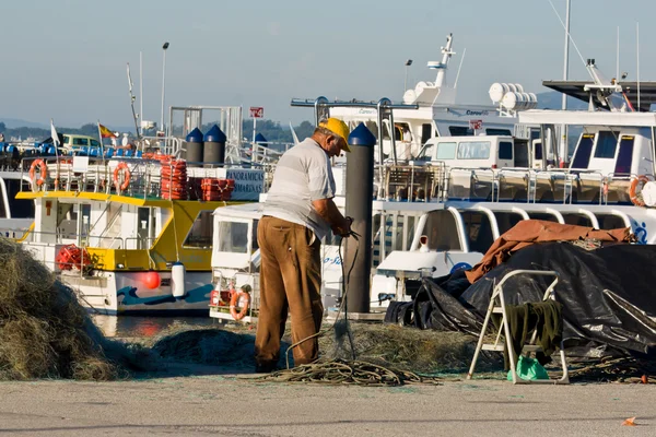 O GROVE, SPAIN - SEPTEMBER 14: Fisherman repairing fishing net on September 14, 2012 in O Grove, Galicia, Spain. The Rias Baixas are a series of four estuarine inlets located on the southwestern coast — Stock fotografie