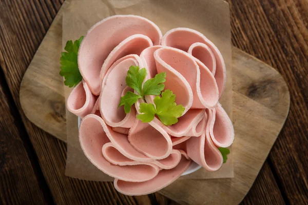 Mortadella fatiada em fundo de madeira — Fotografia de Stock