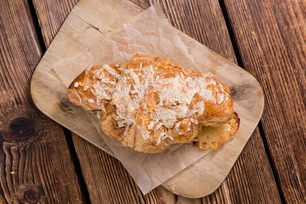Croissant on an old wooden table — Stock Photo, Image