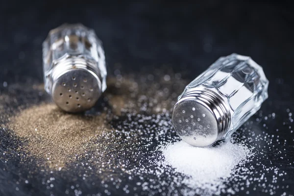 Salt och peppar Shakers på en skiffer platta — Stockfoto