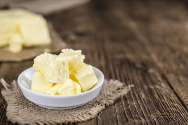 Pieces of Butter on wooden background clipart