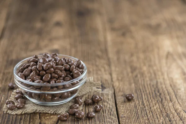 Mesa de madeira velha com passas de chocolate — Fotografia de Stock