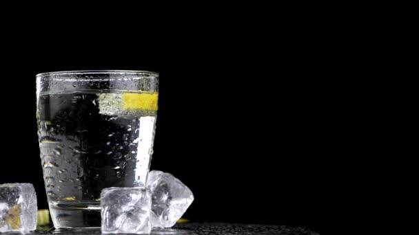 Air Berkilau Dengan Irisan Lemon Dalam Botol Kaca Atas Hitam — Stok Video