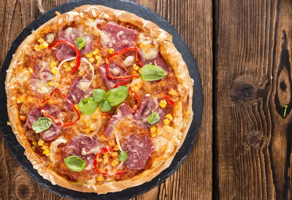 Salami pizza met basilicum op hout — Stockfoto