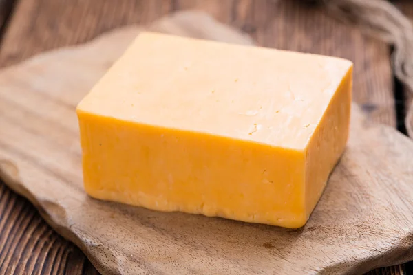 Pezzi di Cheddar (dettagliato primo piano) su sfondo in legno rustico — Foto Stock