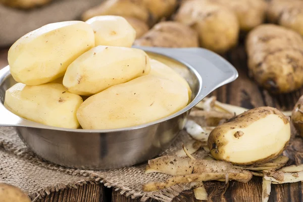 Geschälte Kartoffeln auf hölzernem Hintergrund — Stockfoto