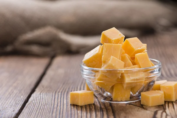 Pieces of Cheddar (detailed close-up shot) on rustic wooden background — Stock Photo, Image