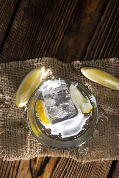 Vodka in glass with lemons and ice — Stock Photo, Image