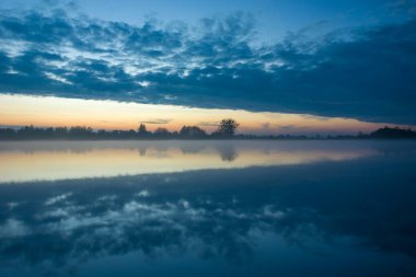 Akşam bulutlarının sisli bir göldeki yansıması, Ekim manzarası.