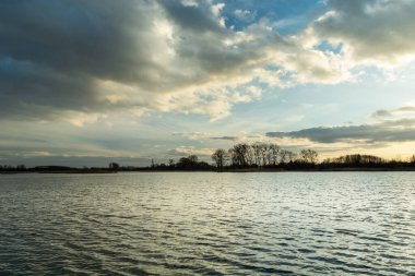 Huzurlu karanlık bir göl üzerinde akşam bulutları