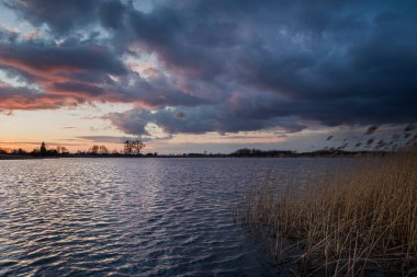 Gölün kıyısındaki koyu bulutlar, akşam manzaralı.