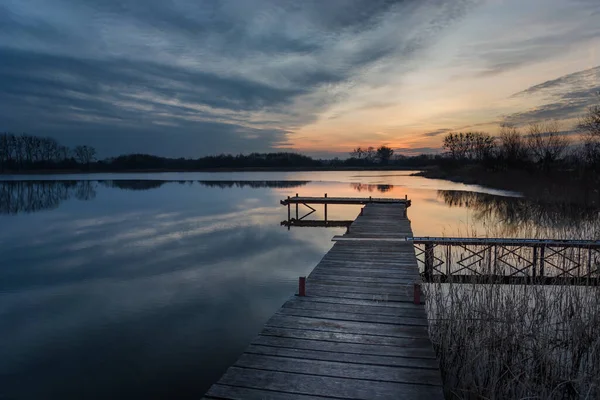 Dlouhý dřevěný most na jezeře a mraky západu slunce — Stock fotografie