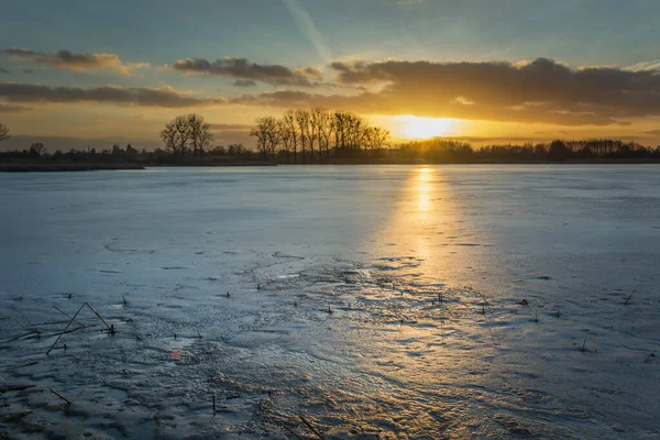 Lago congelado, árvores no horizonte e um belo pôr do sol — Fotografia de Stock