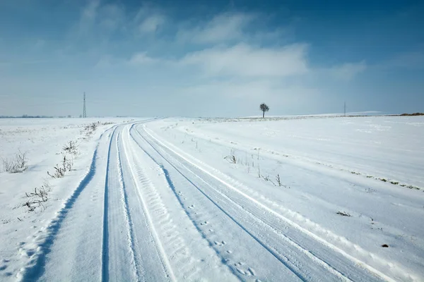 Kırlarda ve mavi gökyüzünde kar yolu, kış güneşli bir gün.
