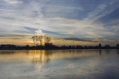 Sunset over a frozen lake, beautiful clouds on the sky
