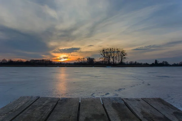 Platform of planks on a frozen lake, beautiful sunset on the sky — Fotografia de Stock