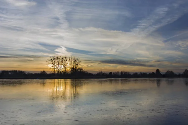 Sunset over a frozen lake, beautiful clouds on the sky — Fotografia de Stock
