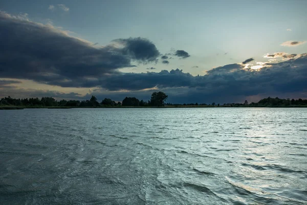 Dark evening clouds at the lake with small waves, Stankow, Poland