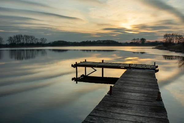 Dřevěná lávka na jezeře a krásné večerní mraky — Stock fotografie