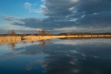 Stankow, Lubelskie, Polonya 'da sakin bir gölün sularındaki kara bulutların yansıması.