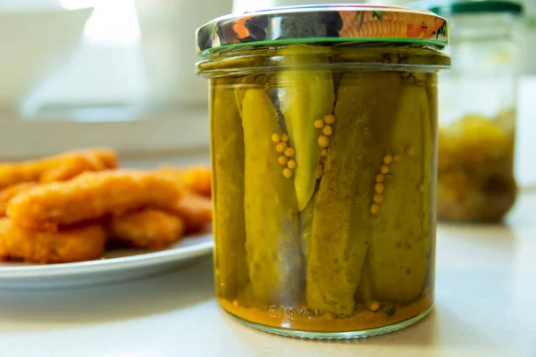Pickled cucumbers in a jar and fish sticks — Stok Foto