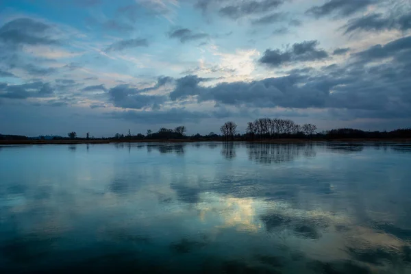 Reflection of evening clouds in a frozen lake, Stankow, Poland