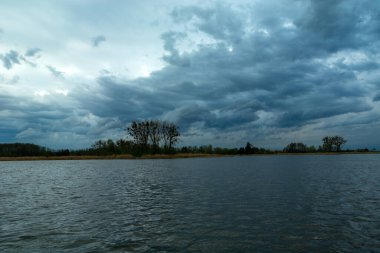 Durgun bir göl üzerinde huzursuz akşam bulutları, Stankow, Polonya 'da bahar manzarası