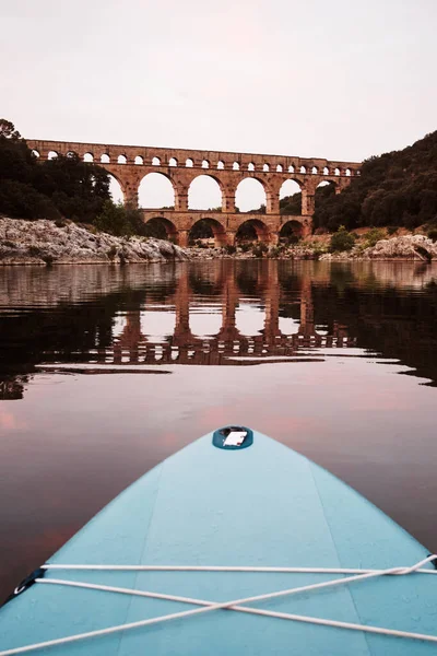Fransa 'daki Provence nehrindeki Pont-de-Gard su kemerinde ayakta sörf tahtasından bakış açısı. Yüksek kaliteli dikey fotoğraf. 