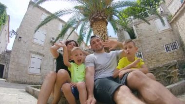 Beyaz güzel ailenin portresi - Mutlu aile, yaz tatilinde kameraya eğilip gülümseyen ve el sallayan bir video kaydediyor. Açık hava.