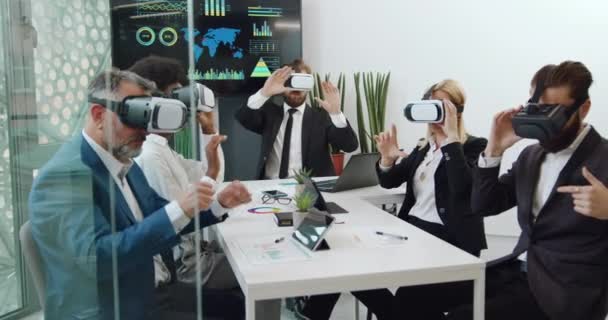 Primer plano de compañeros de trabajo corporativos multiétnicos profesionales de buena apariencia que trabajan en la pantalla imaginaria con auriculares de realidad virtual en la sala de juntas — Vídeo de stock
