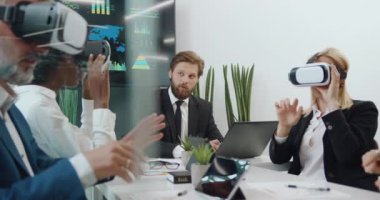 Ortak proje üzerine sanal gerçeklik kulaklığı takan ve bilgisayardan veri girişi yapan sakallı şefleriyle konuşan çekici, yüksek yetenekli uluslararası takım.