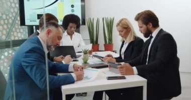 İyi görünümlü, çalışkan, üst düzey uluslararası uzman ekibinin portresi toplantı odasındaki i-pad 'lerden alınan belgeler ve verilerle birlikte çalışıyor.