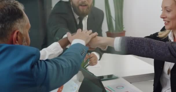 Retrato de atractivo éxito en buen humor equipo internacional de hombres y mujeres que se apilan las manos juntos antes de comenzar el trabajo conjunto sobre el proyecto de negocios en la sala de juntas — Vídeos de Stock