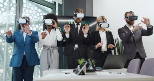 Ritratto di cinque collaboratori aziendali multirazziali altamente qualificati e concentrati in cuffie di realtà virtuale che lavorano su uno schermo immaginario davanti alla telecamera in una moderna sala ufficio — Video Stock