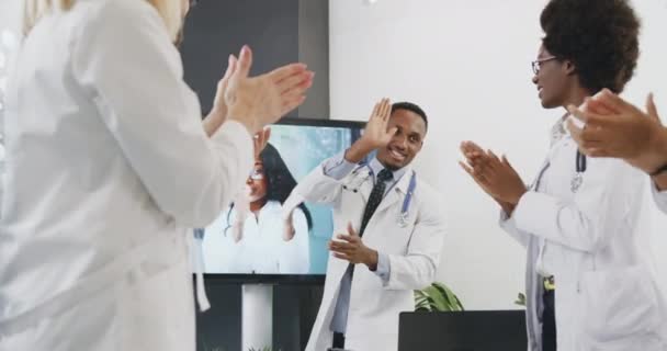 Aantrekkelijke ervaren positieve succesvolle diverse medische mensen begroeten elkaar met high five na right get beslissing tijdens videoconferentie met vrouwelijke collega — Stockvideo