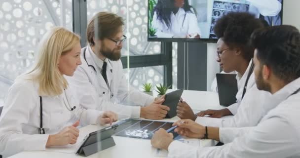 Probable seguro de éxito experimentados médicos de raza mixta hablando entre sí en la sala de juntas durante la reunión, cámara lenta — Vídeo de stock