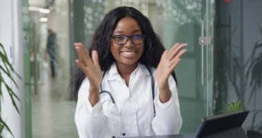 Mutlu, çekici, deneyimli, başarılı, siyah tenli kadın doktoru yakından çek. Bu doktor, meslektaşlarını sağ eliyle alkışlıyor. Online konferans sırasında tedavi görüyor.