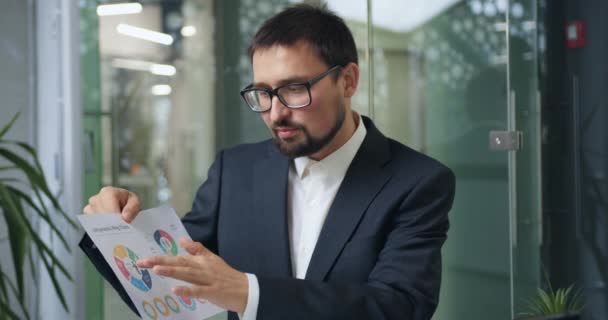 Guapo hombre de negocios barbudo confiado que celebra conferencia en línea usando gráficos de anillo de infografías con sus socios, cámara lenta — Vídeo de stock