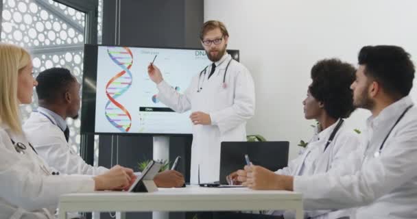 Probabile medico barbuto esperto di successo che tiene una presentazione sullo schermo interattivo sul tema del DNA per i suoi colleghi maschi e femmine multirazziali, da vicino — Video Stock