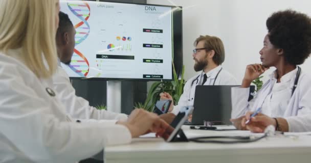Etkileyici başarılı, üst düzey, çok ırklı tıp çalışanları toplantı yapıyor. DNA teması üzerine toplantı yapıyorlar. Toplantı odasındaki interaktif ekranda. — Stok video