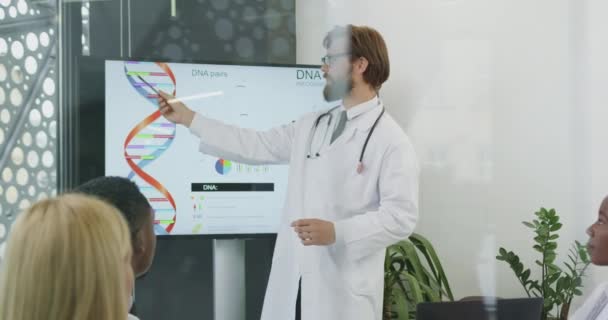 Concept médical où attrayant positif élevé qualifié médecin barbu expliquant la structure de l'ADN pour ses collègues masculins et féminins dans la salle de réunion — Video