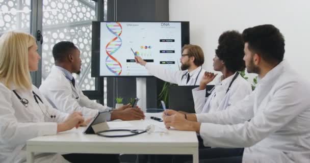 Sympaticky koncentrovaný úspěšný cvalified mezinárodní tým lékařů pořádající prezentaci na téma DNA během semináře v konferenční místnosti, zpomalený film — Stock video