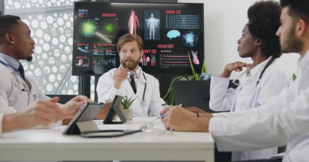 Likable confident professional international group of medics consists of three men and two women discussing different versions of treatment after watching results of patients x-ray — Stock Video