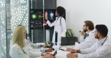 Yüksek yoğunlukta melez ırk doktorları, kadın siyah tenli meslektaşlarından iç organ teması üzerine dijital sunum izliyorlar.