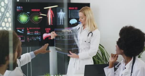 Medical concept where likable concentrated experienced diverse medical colleagues advising together with their female head doctor while revisioning x-ray image — Stock Video