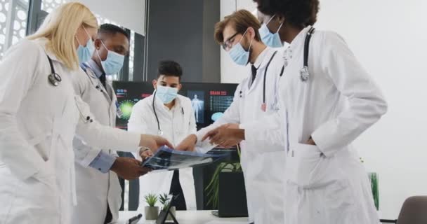 Concepto médico en el que un atractivo grupo multirracial de médicos con máscaras trabajando juntos durante la pandemia de covid-19 en la sala de conferencias — Vídeos de Stock