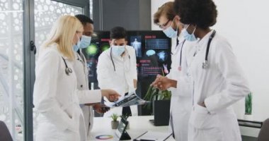 İyi görünümlü, kendine güvenen, maskeli karışık ırk doktorlarının portresi. Toplantı odasında brifing sırasında el sıkışarak selamlaşıyorlar. Çalışma anlayışı, covid-19.