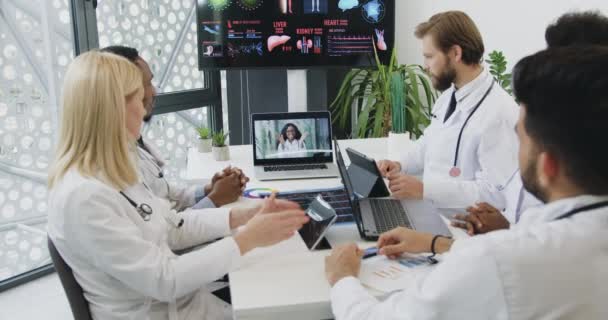 Beau regard satisfait confiant cvalifié divers médecins saluant avec applaudissements après la fin réussie de la vidéoconférence en ligne avec leur médecin en chef féminin — Video