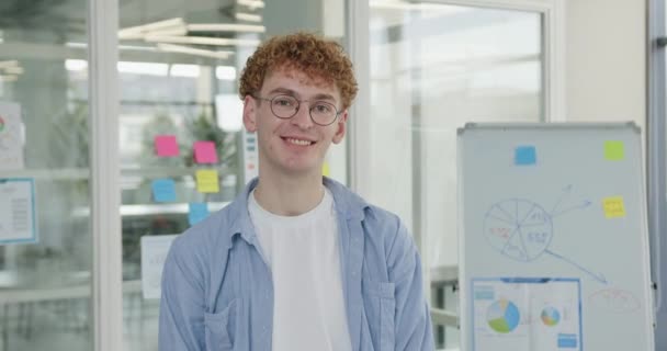 Irodai munka koncepció, ahol jóképű mosolygós magabiztos fiatal férfi irodai dolgozó szemüvegben nézi a kamerát a modern irodai szobában — Stock videók